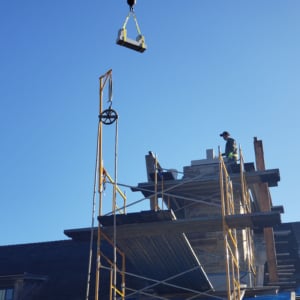 Construction worker operating crane to lift materials on a building site, showcasing Kraneworks' professional crane services in action.