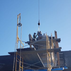 Construction workers using a crane to lift materials at a building site, showcasing KraneWorks crane services in action.