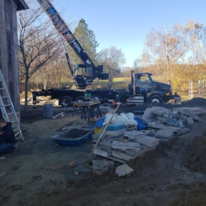 Crane truck on construction site with tools and materials, showcasing Kraneworks' crane services for residential projects.