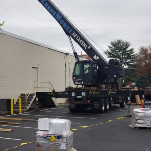 CraneWorks crane positioned in a parking lot ready for operation, showcasing crane services for commercial projects with materials stacked nearby.