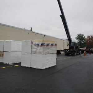 Cranes lifting materials at a construction site with stacked pallets in the foreground, showcasing KraneWorks' professional crane services for commercial projects.