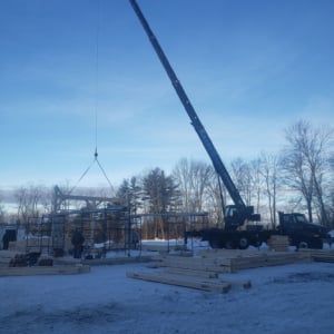 Cranes lifting materials at a construction site in winter, showcasing Kraneworks' professional crane services for commercial projects.