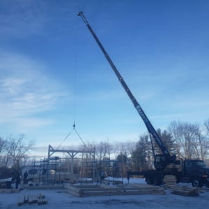 Crane lifting construction materials at a job site during winter, showcasing KraneWorks' professional crane services in action.