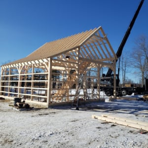 Construction of a wooden structure with crane in the background, showcasing KraneWorks crane services in action for commercial project.