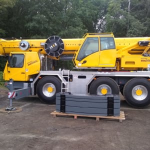 Yellow crane truck parked on a construction site, showcasing crane features and equipment, representing Kraneworks' professional crane services for various projects.