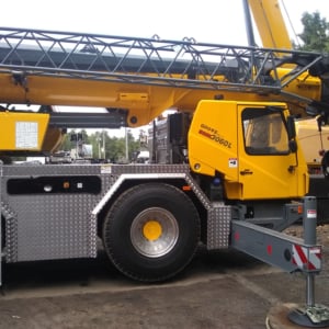 Yellow crane truck showcasing professional crane services by Kraneworks, featuring a robust design and operational features in a construction setting.