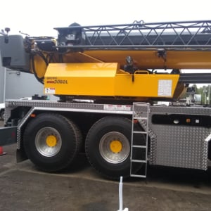 Crane truck showcasing Kraneworks' professional crane services, featuring a yellow boom and large wheels, set in a construction environment.