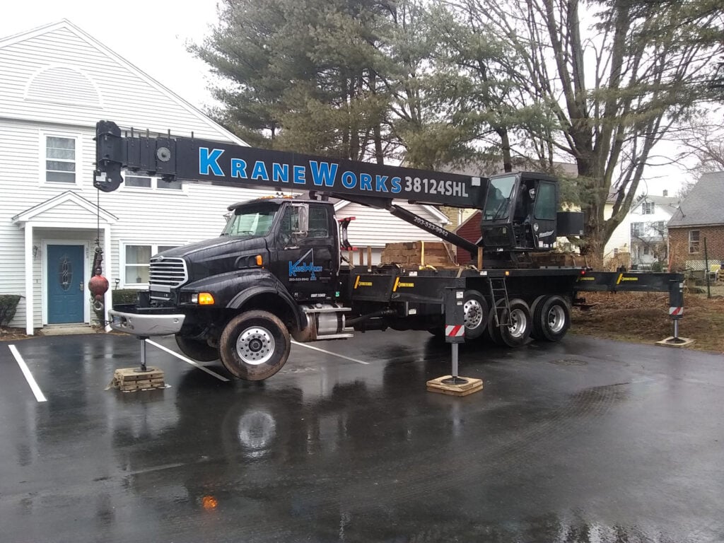 CraneWorks truck-mounted crane parked in residential area, showcasing professional crane services for construction and rigging projects.